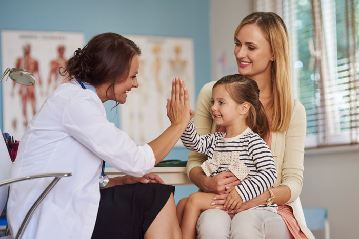 young happy doctor high fiving little girl after open enrollment